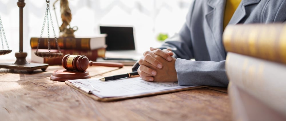 Best motorcycle accident lawyer in Syracuse reviewing legal documents with gavel and scales of justice.