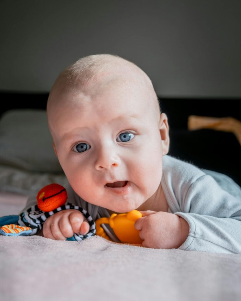 Baby playing with toys, showing signs of recovery from Cephalohematoma birth injury.