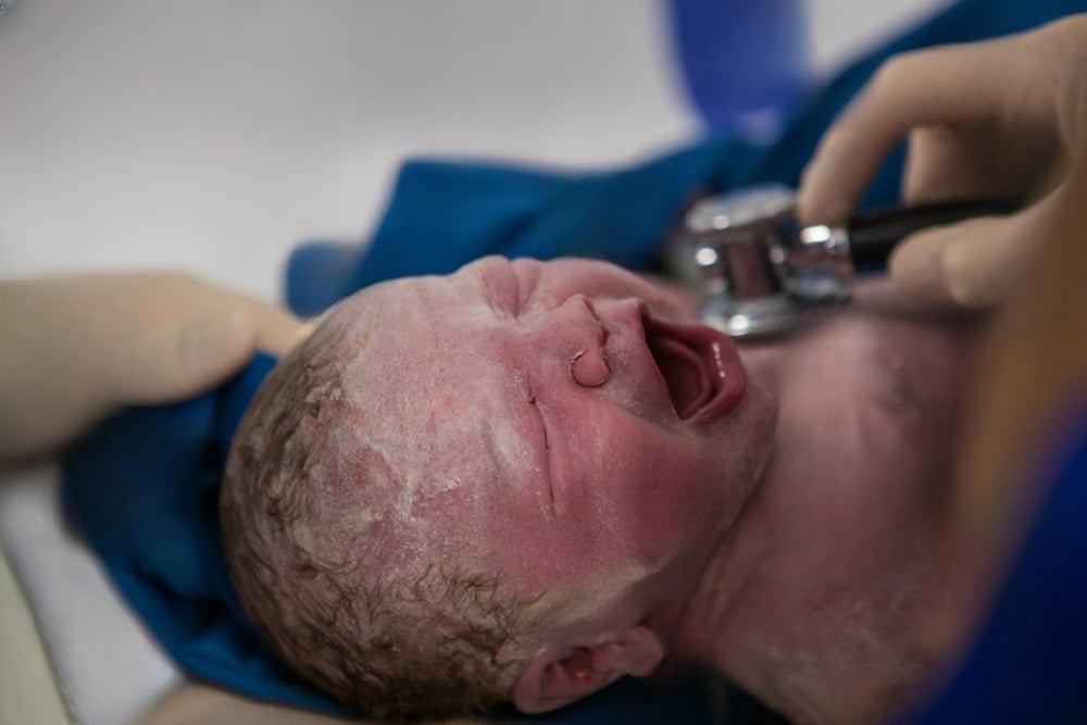 Newborn crying after delivery, potentially due to failure to act during labor.