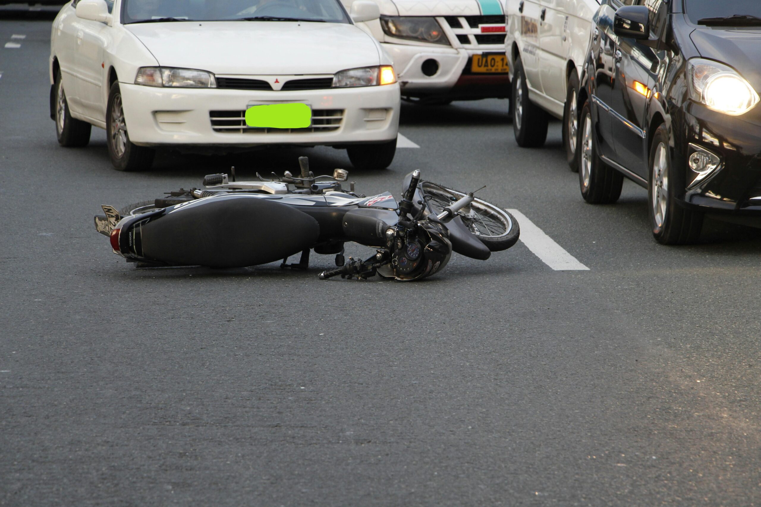 Motorcycle accident scene with fallen bike and traffic stopped behind on highway.