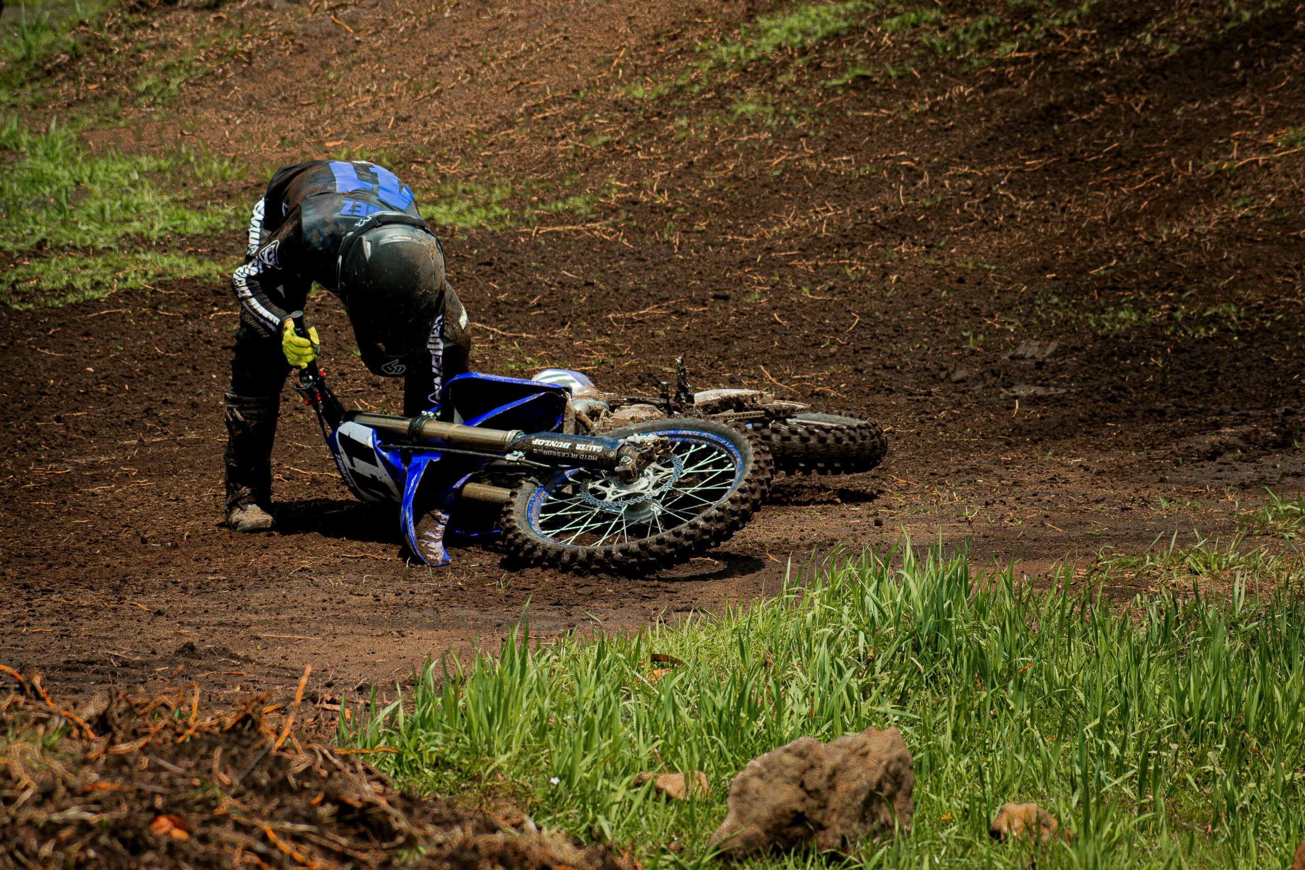 Motorcyclist lifting crashed dirt bike after accident showing chances of motorcycle crashes
