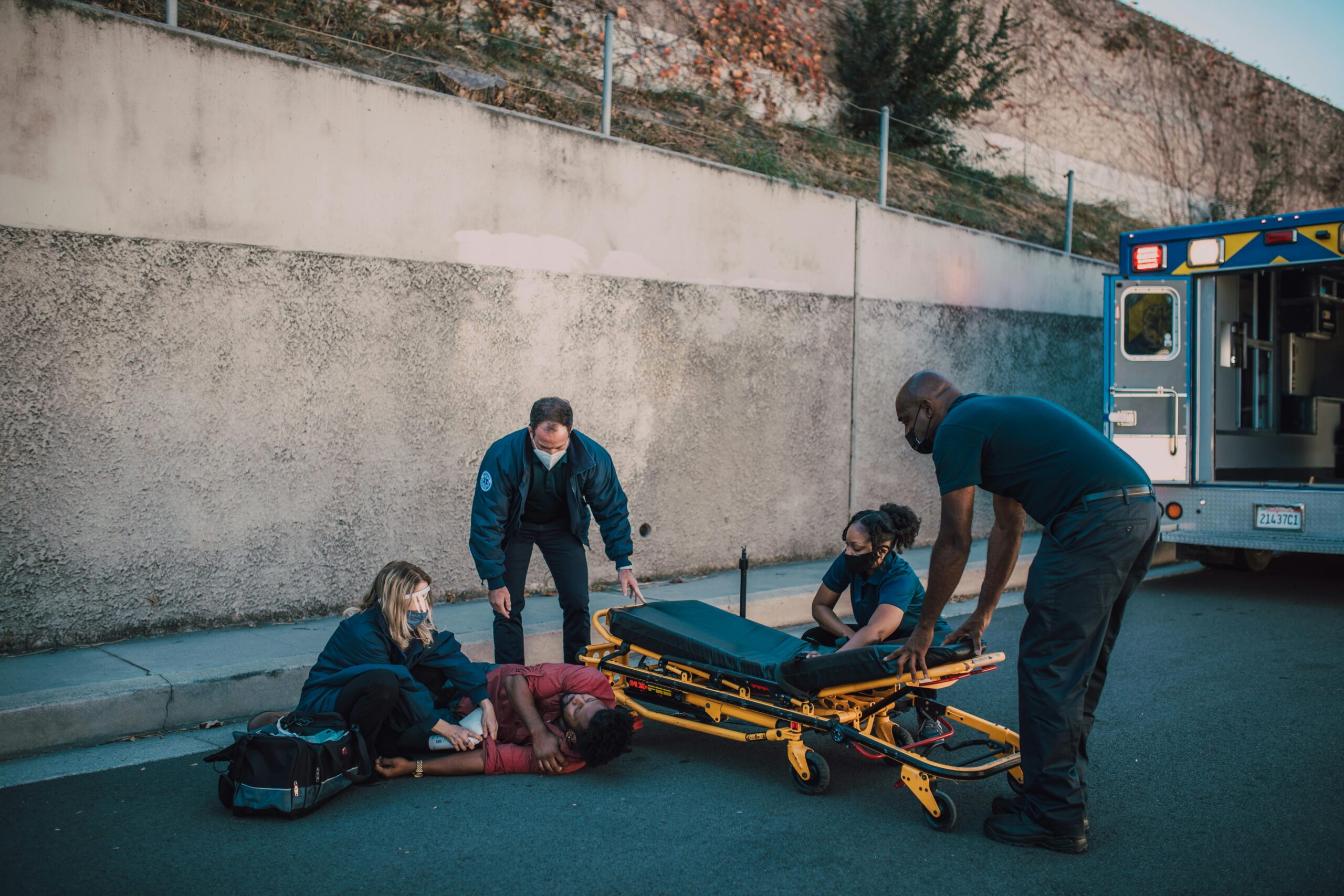 Personal Injury scene with paramedics assisting injured person on street near ambulance