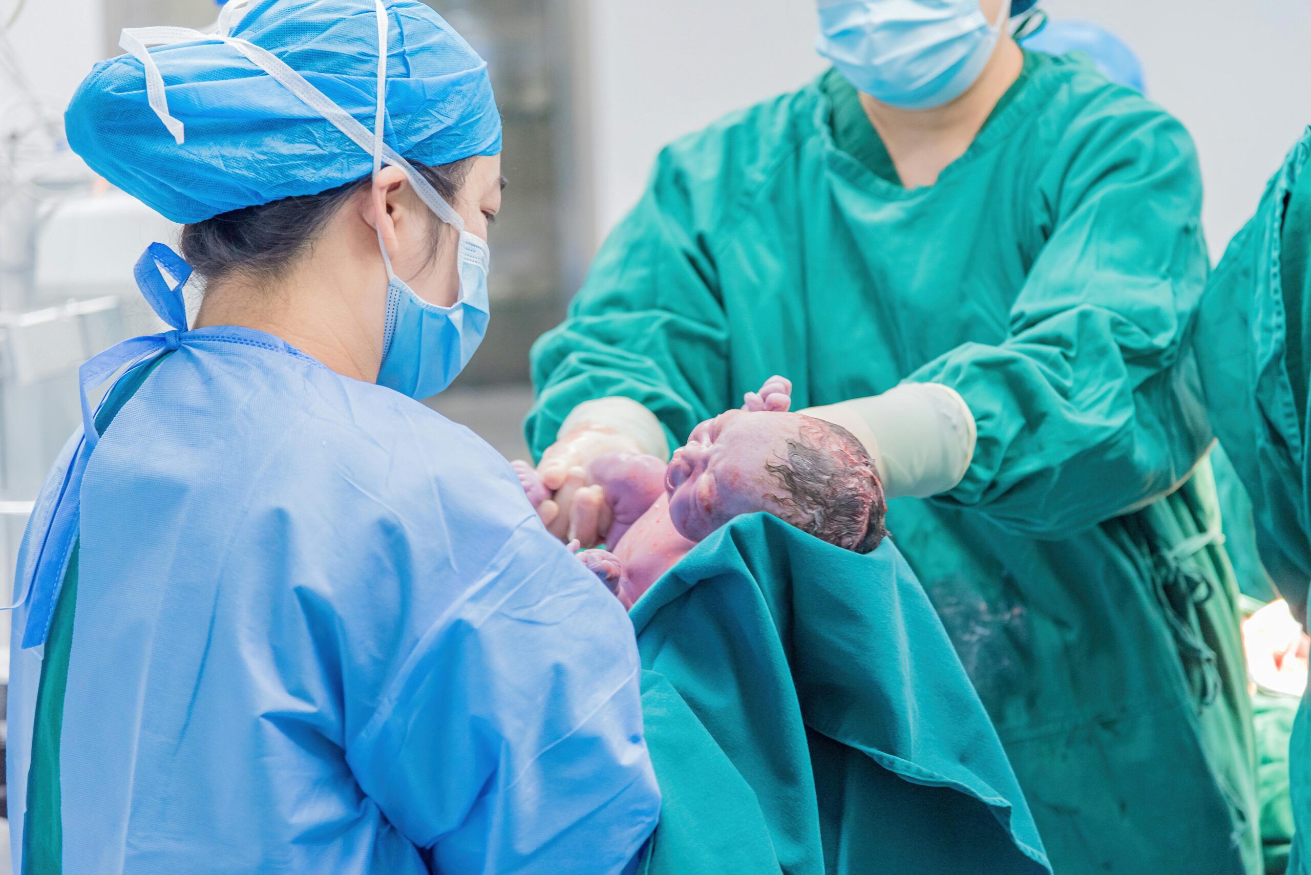 Doctors delivering newborn baby during hospital birth procedure with medical team assistance