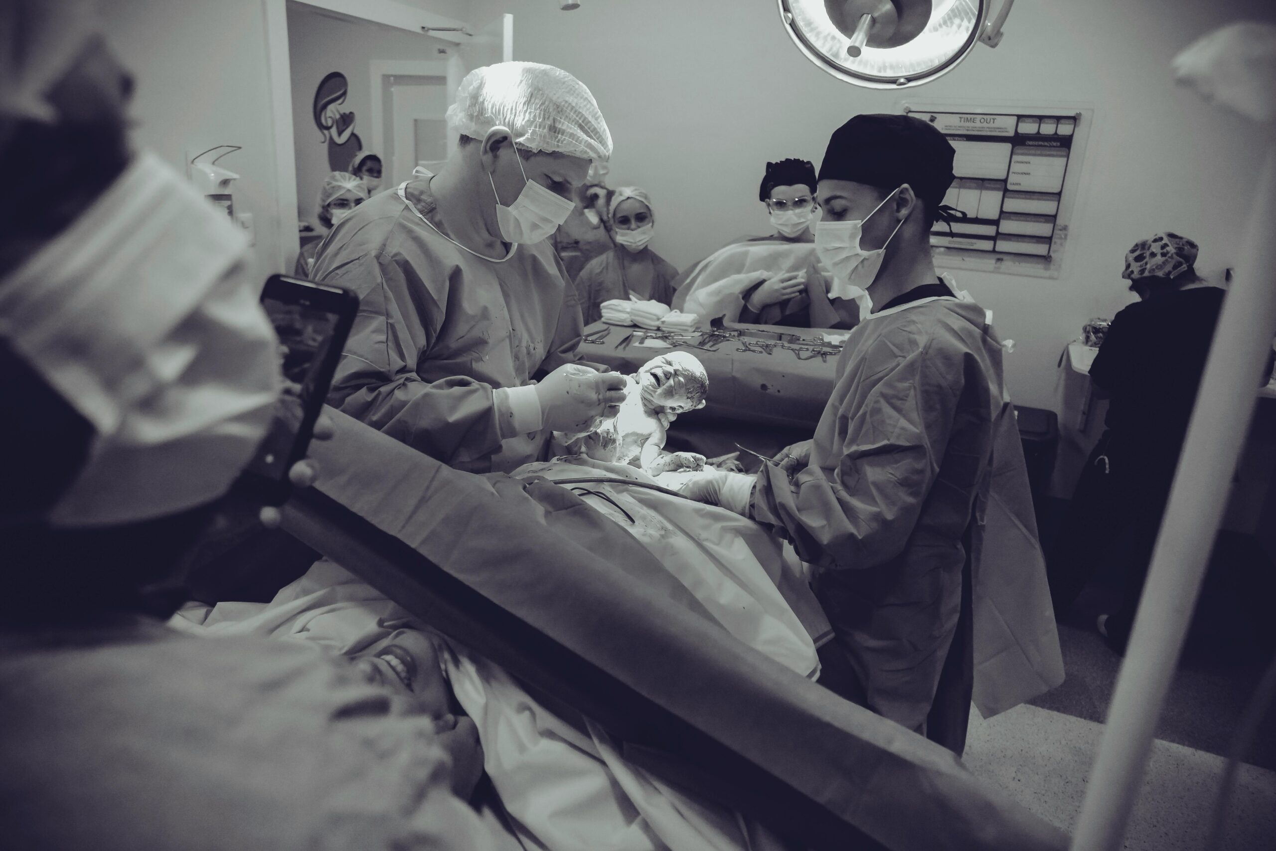 Medical team performing childbirth delivery in hospital operating room with newborn infant