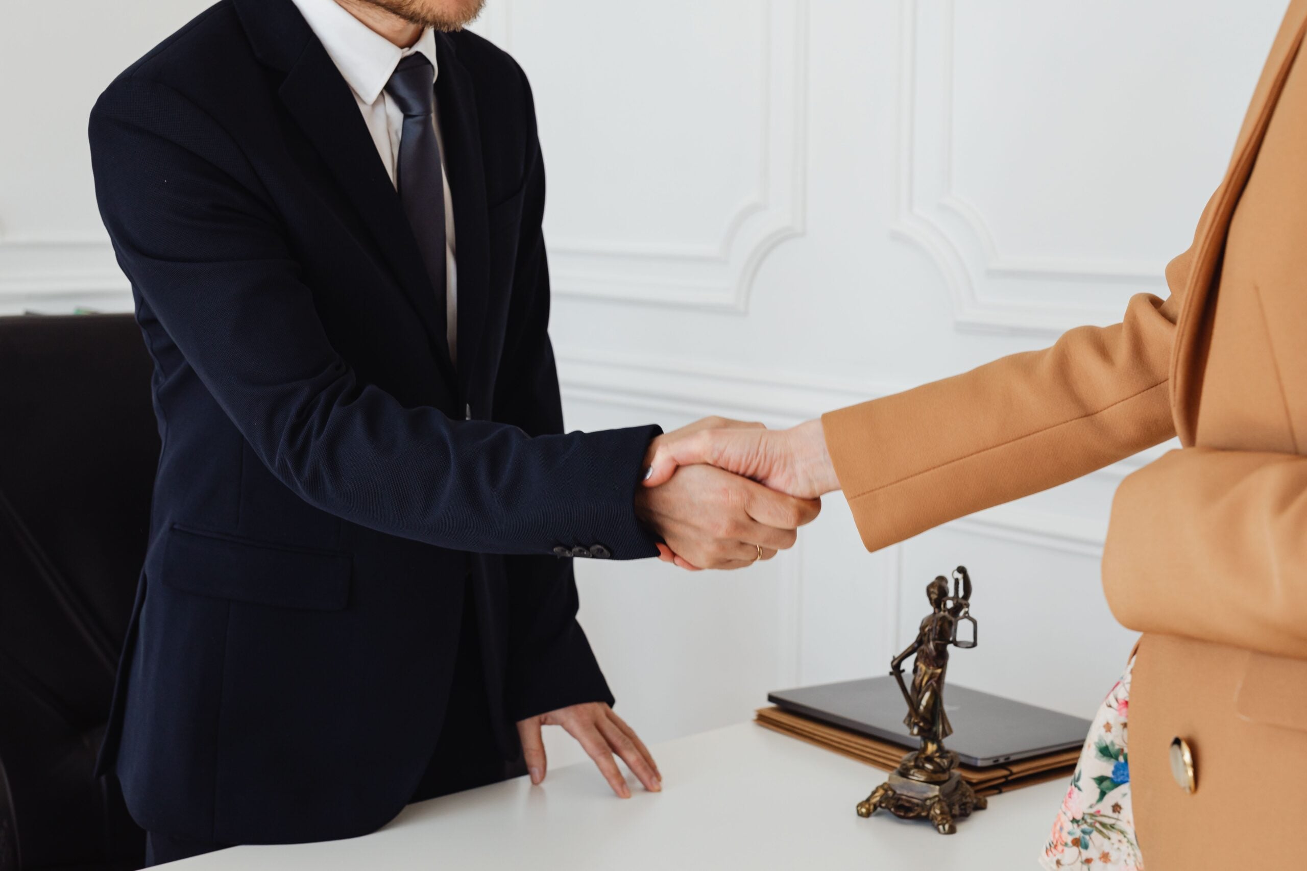 Professional handshake during a personal injury settlement meeting between a lawyer and client in a legal office.