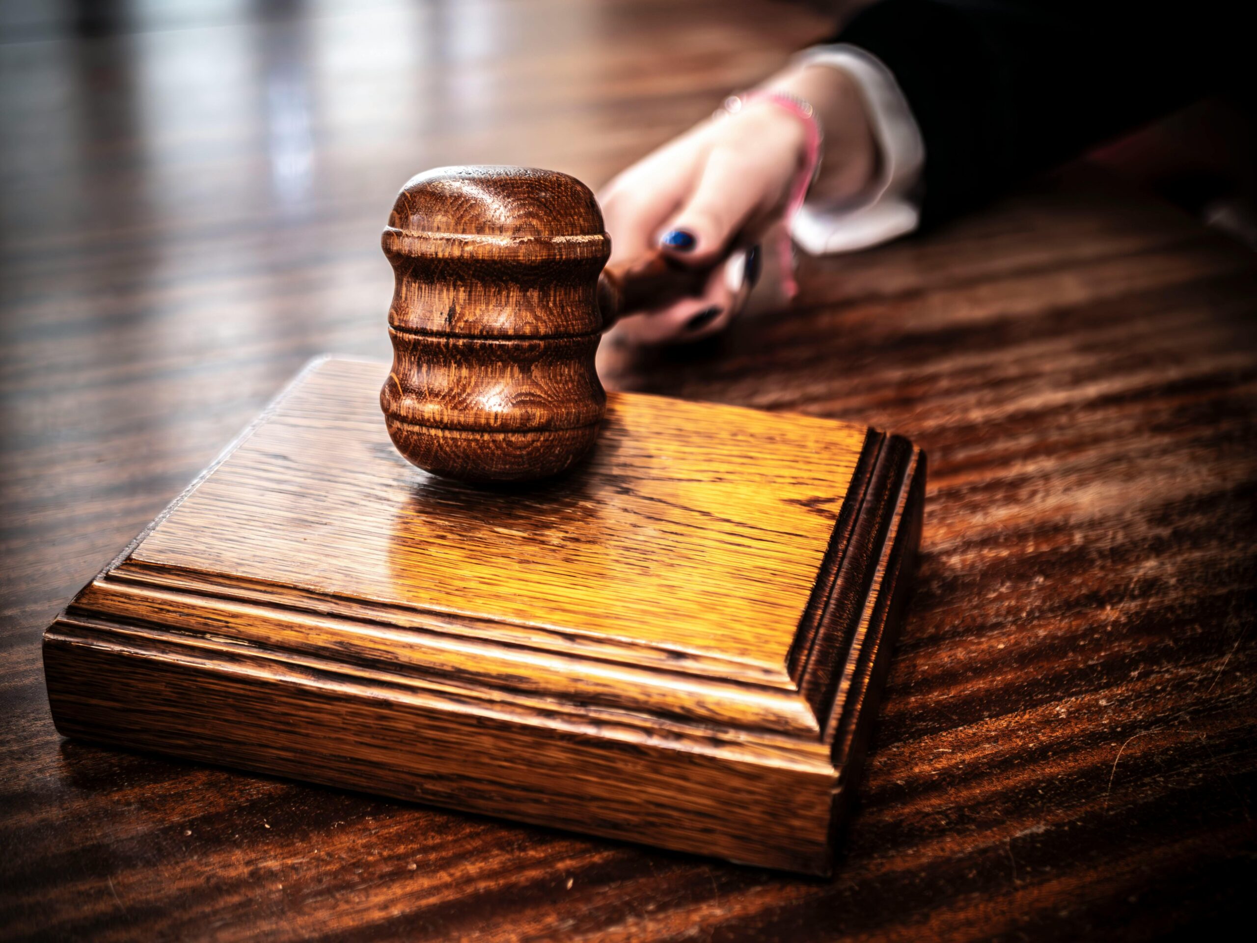 Judge striking wooden gavel in courtroom during legal hearing or premises liability case proceeding.