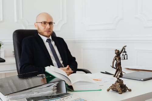 Wrongful Death Lawyer in an office with legal books and a Lady Justice statue.