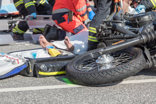 Emergency responders assisting injured motorcyclist after serious road accident scene
