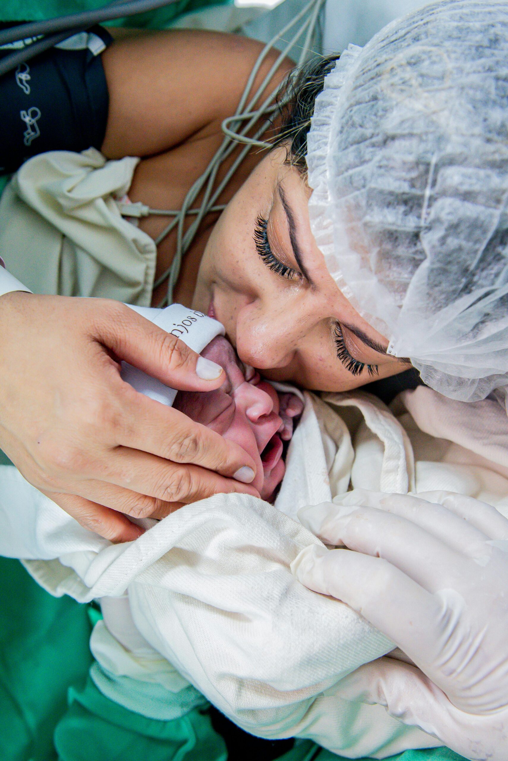Mother lovingly holding and kissing her newborn baby shortly after birth.