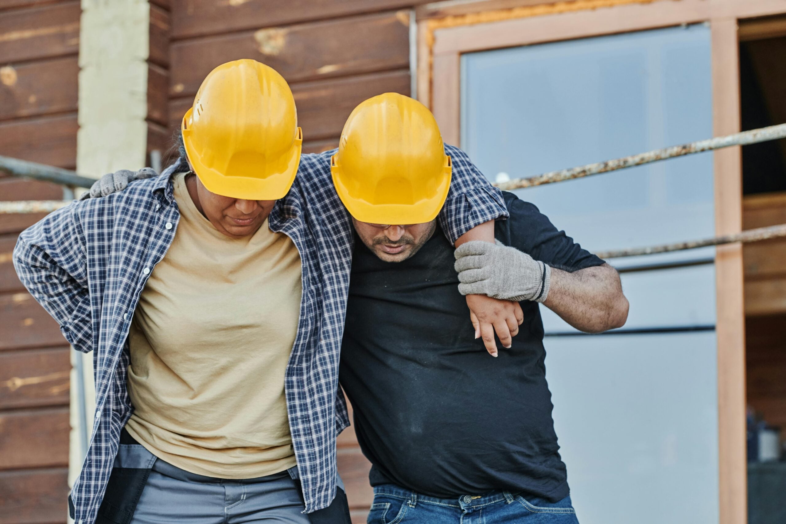 Injured construction worker being assisted by coworker while leaving a residential job site