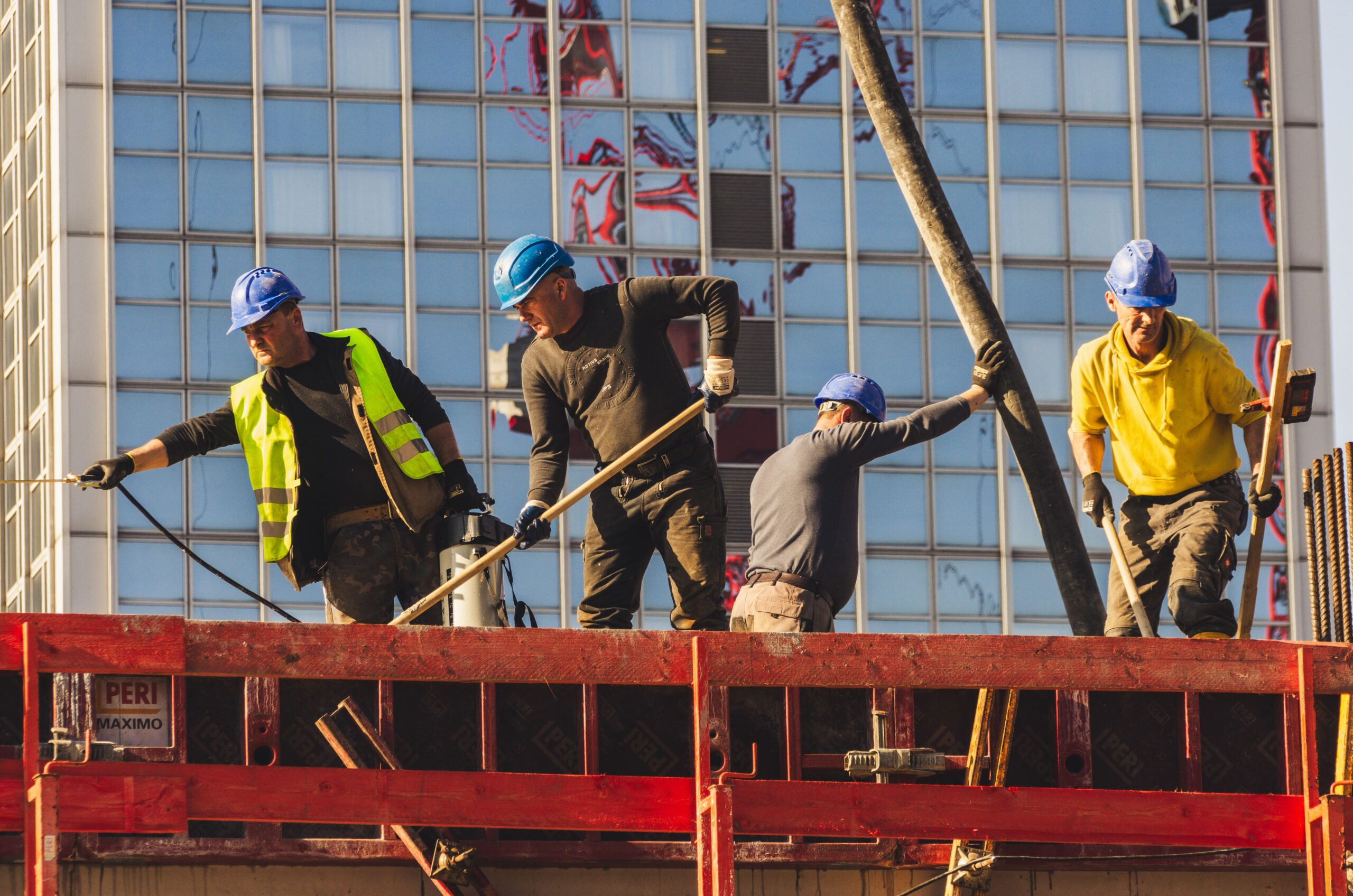 Construction workers pouring concrete on an elevated building site in an urban area