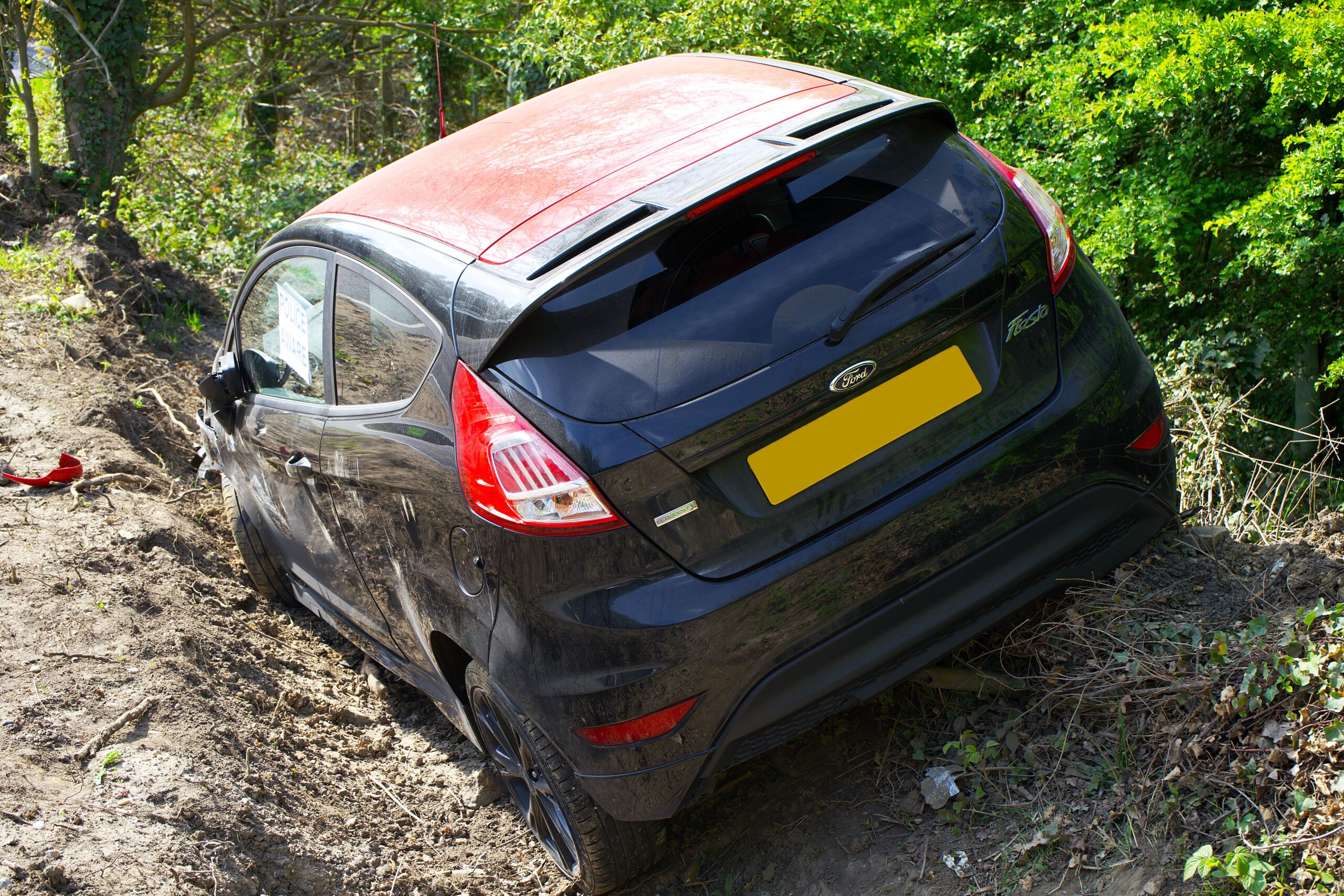 Close-up of black car off-road crash, highlighting damage after a car accident