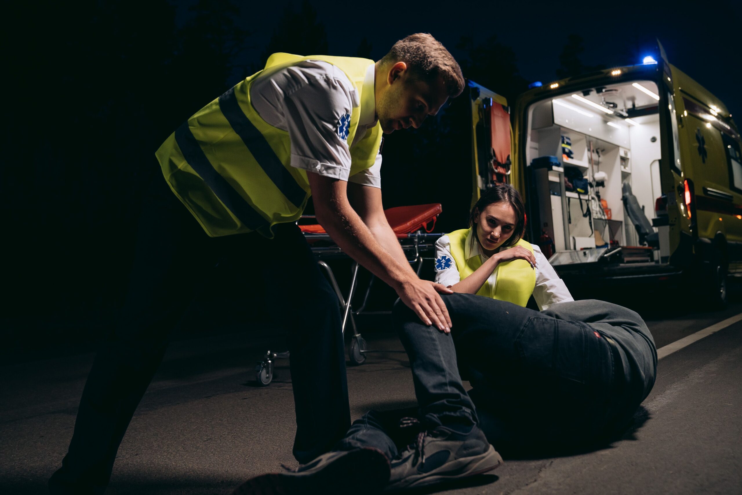 Paramedics providing emergency medical assistance to an injured person beside ambulance